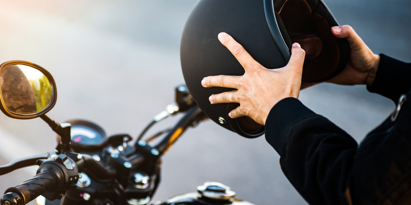 Image of someone sitting on a motorcycle and putting on a helmet