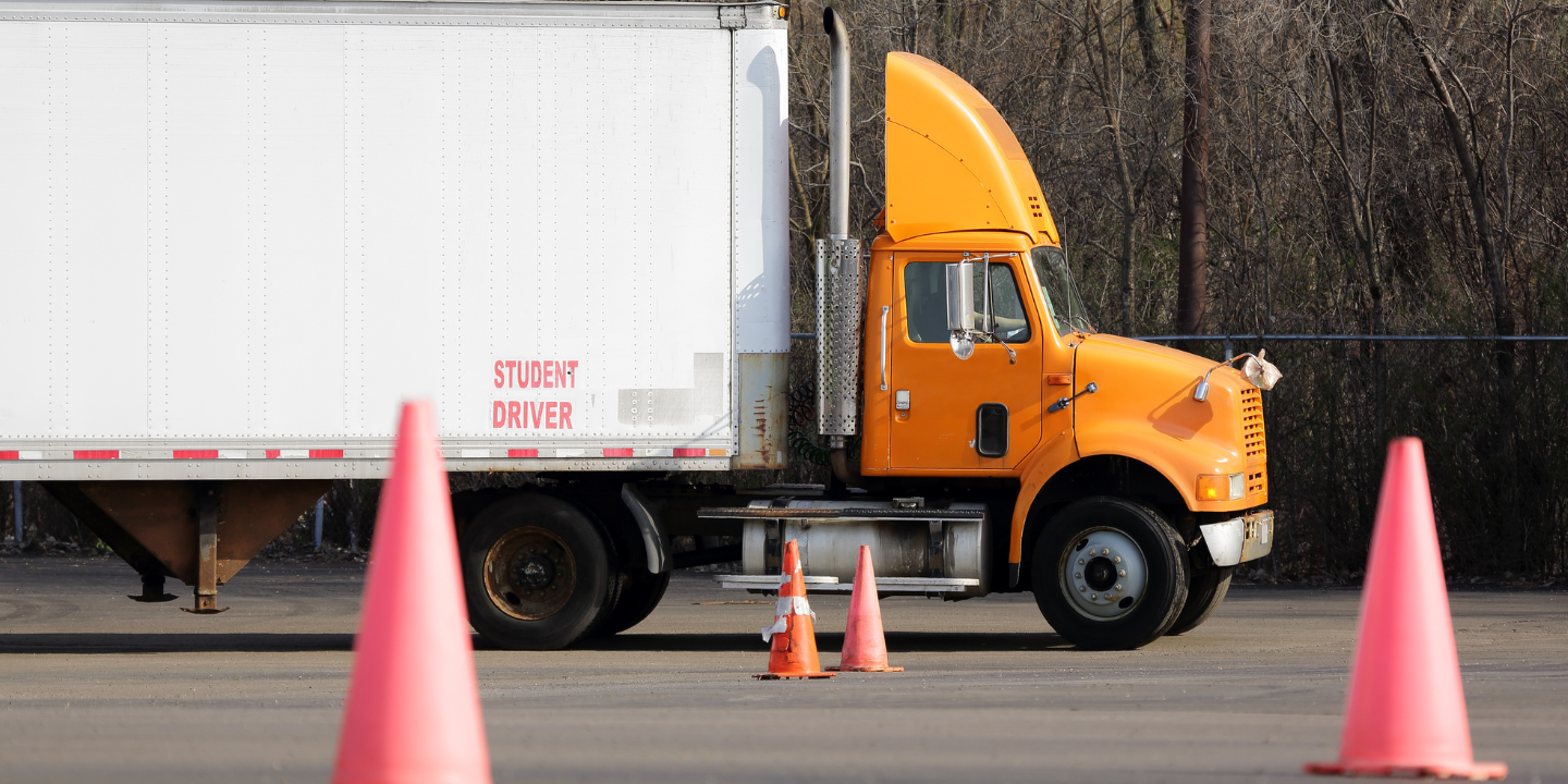 Image of a semi-truck in a parking lot surrounded by orange traffic cones