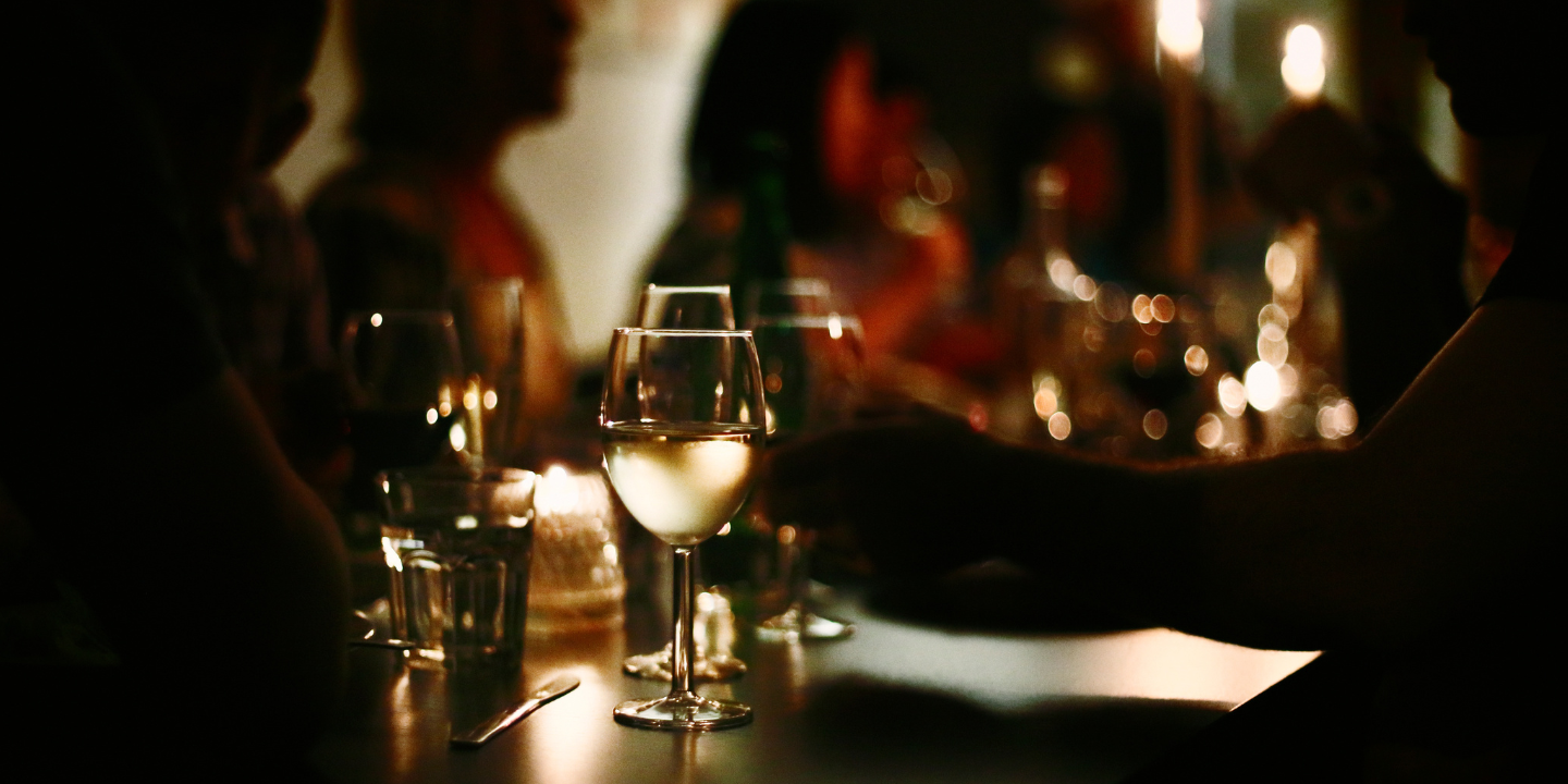 Image of a pair of wine glasses on a bartop in a darkly lit restaurant