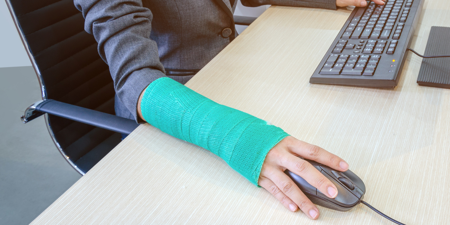 Image of someone in an arm cast sitting at a computer