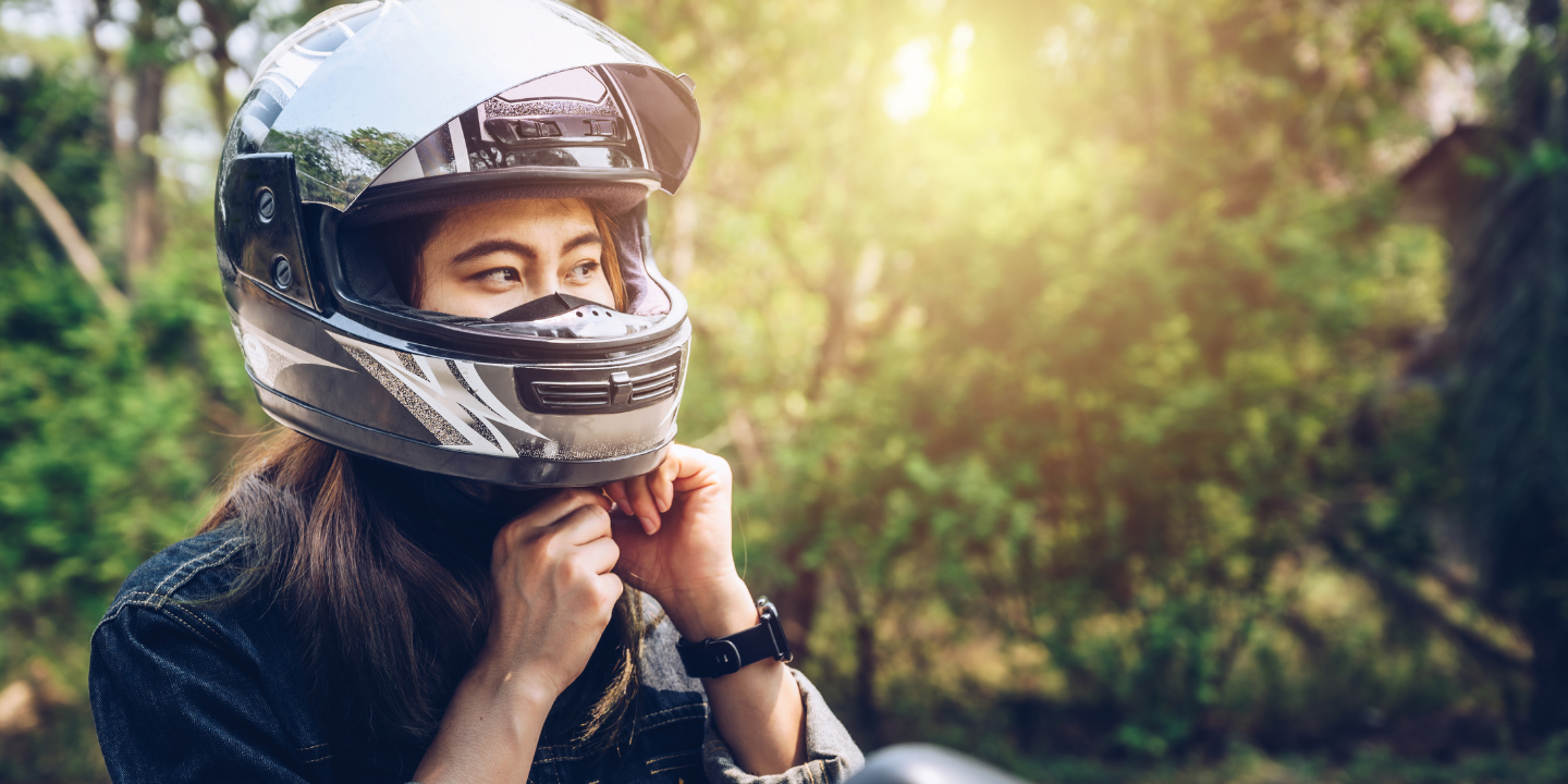 Image of a woman putting on a motorcycle helmet